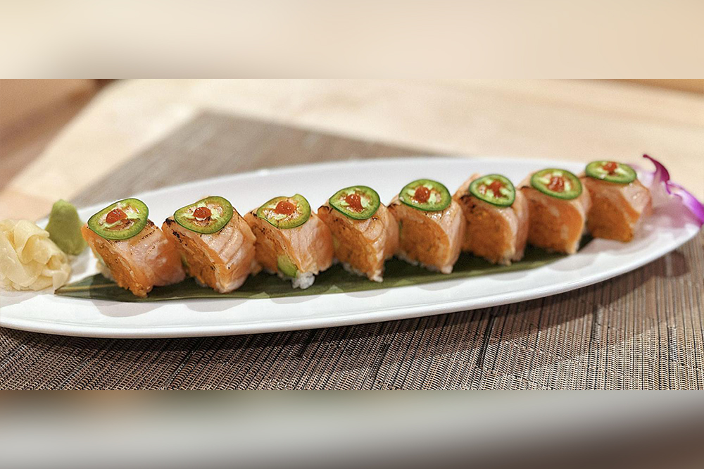Seared salmon jalapeno sushi roll served on a white platter